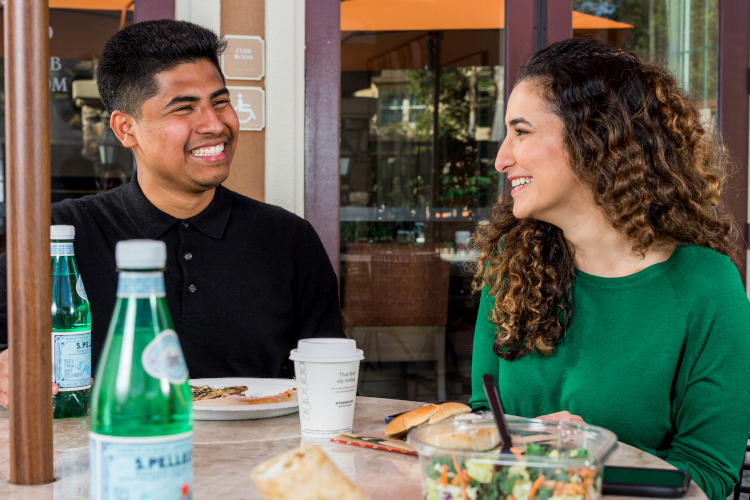 Two people smiling and eating at a table