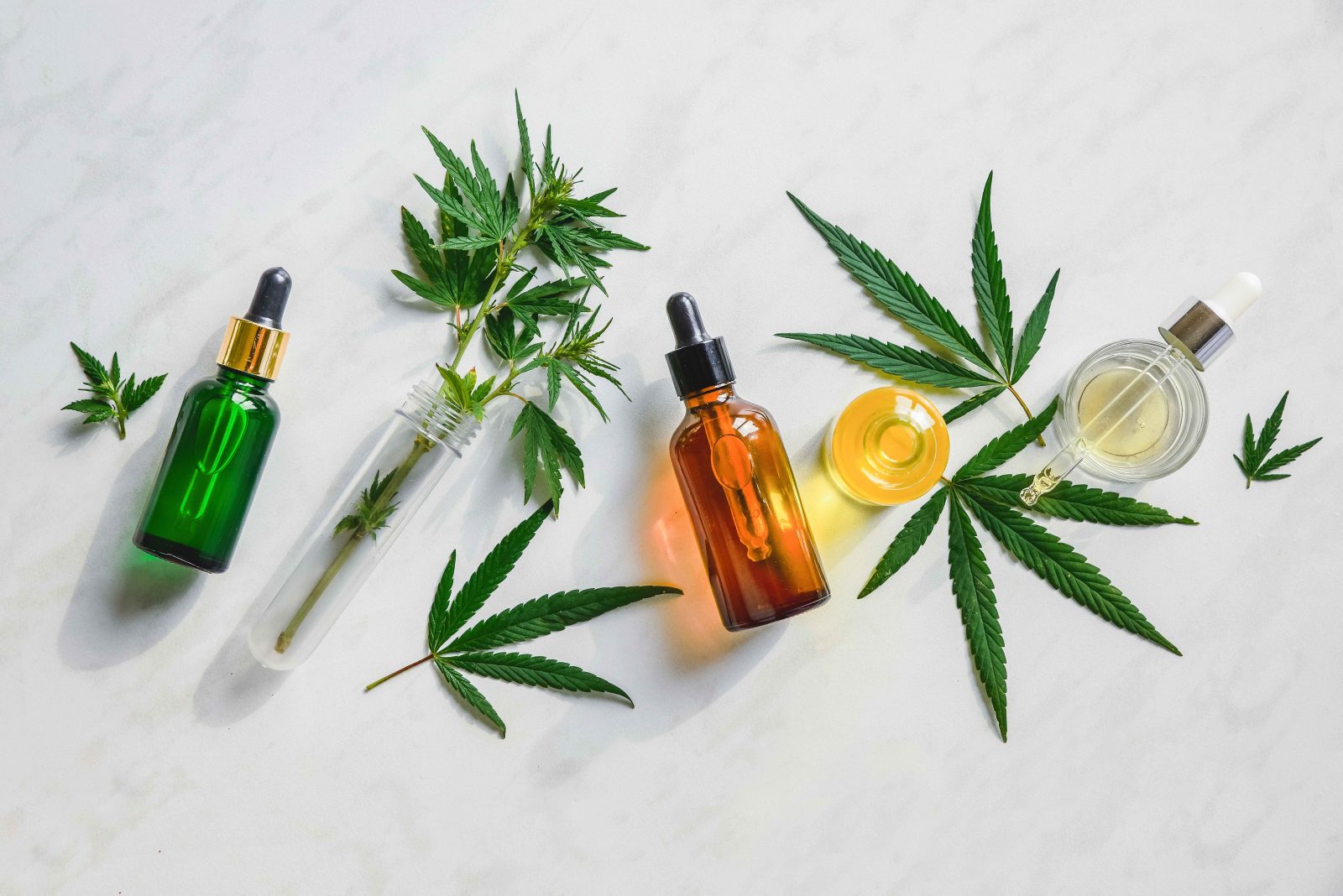 Various glass bottles with CBD oil, THC tincture and hemp leaves.