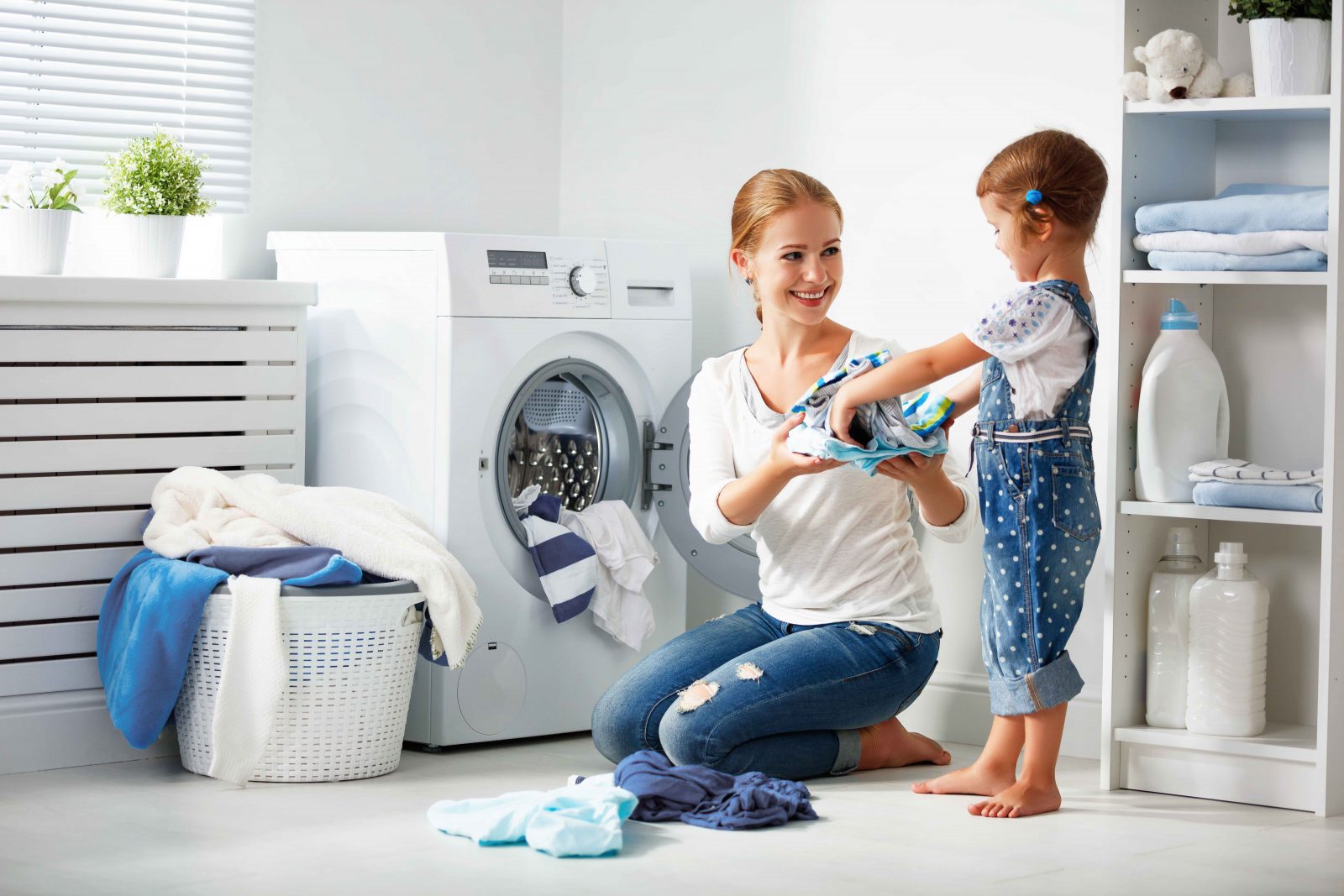 family mother and child girl little helper in laundry room near washing machine and dirty clothes
