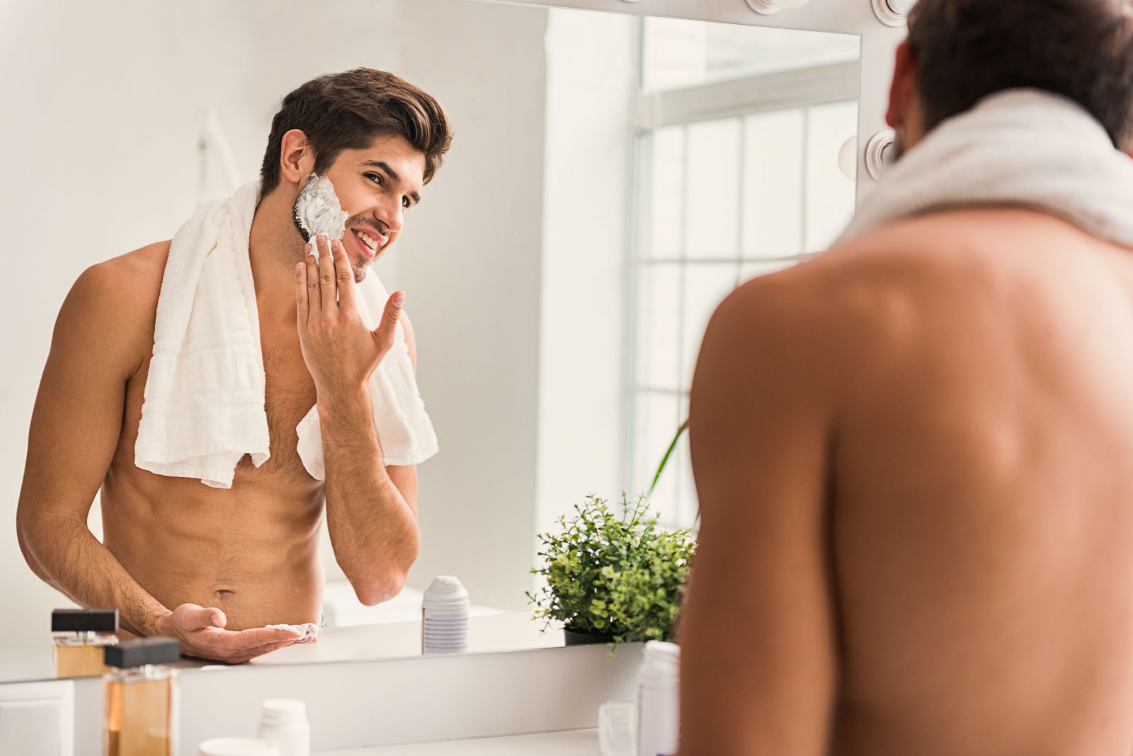 Man preparing to shave, wiping shaving cream on his beard