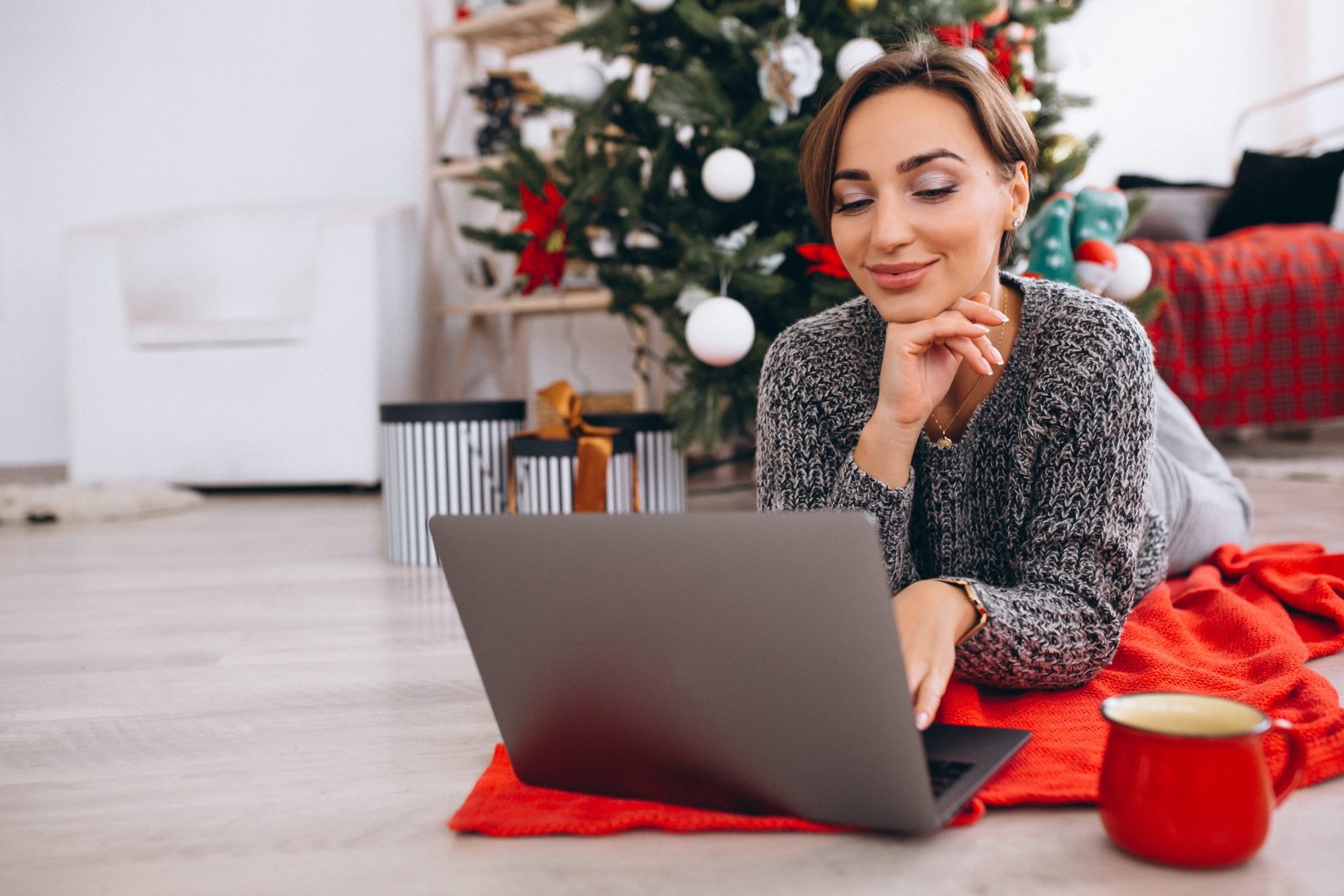 A woman shops online in front of her Christmas tree