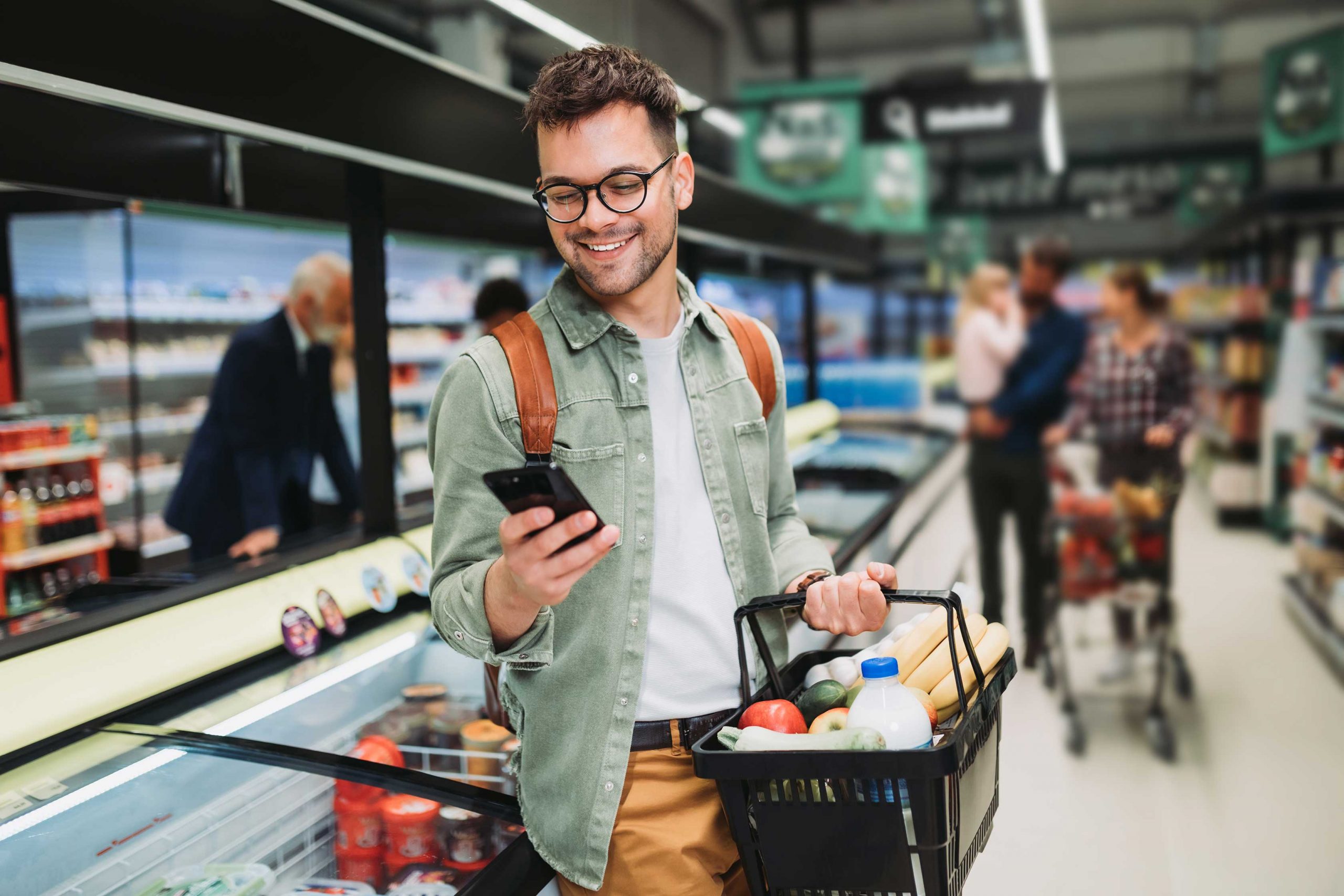 Man checks his phone while shopping at the grocery store.