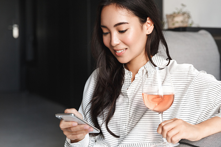 Woman holding wine and browsing phone