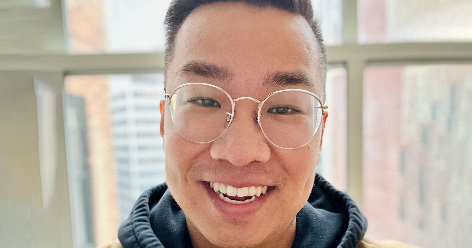 A male asian american wearing glasses and smiling.