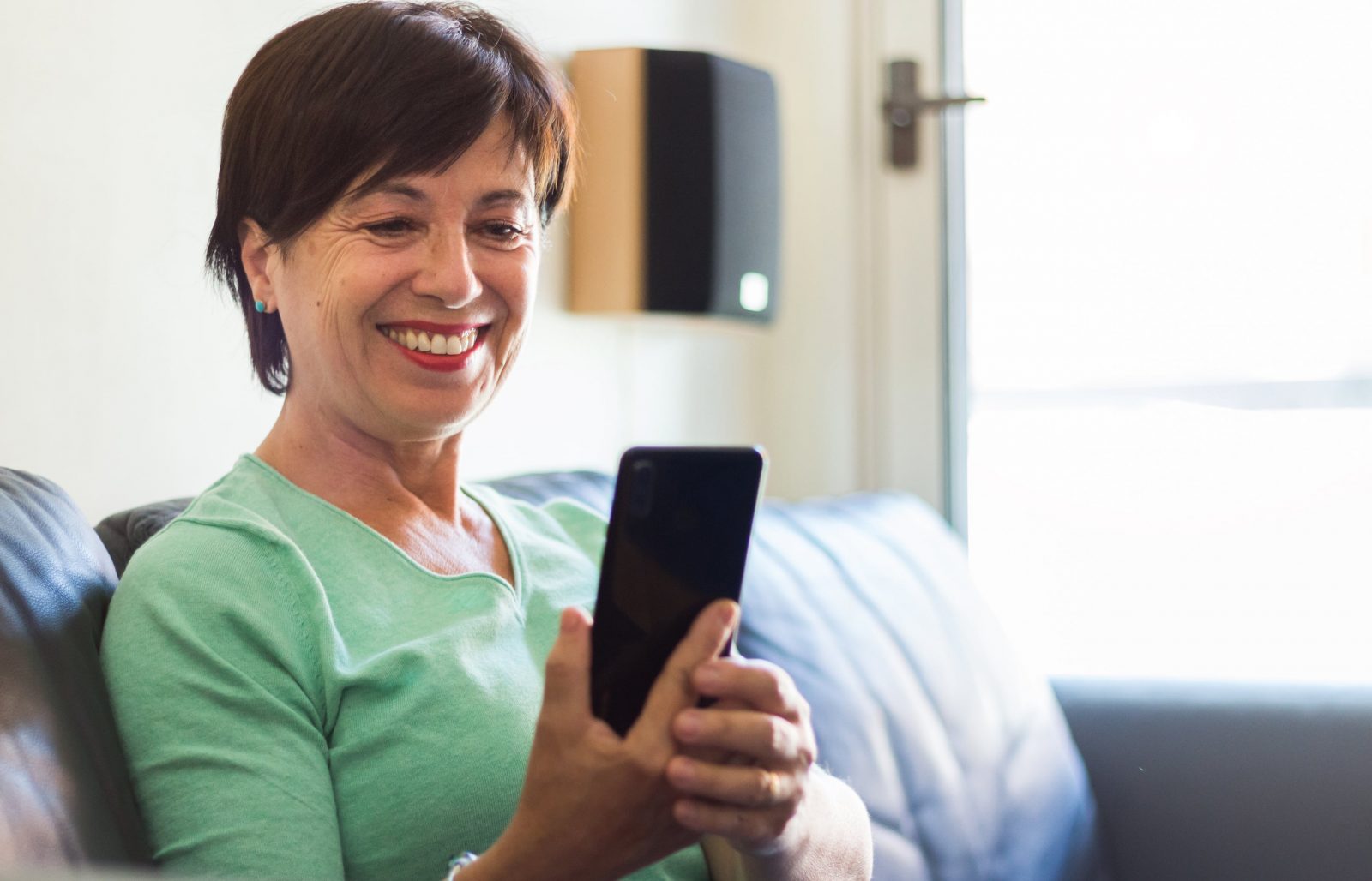 Smiling woman looking at her phone on a couch