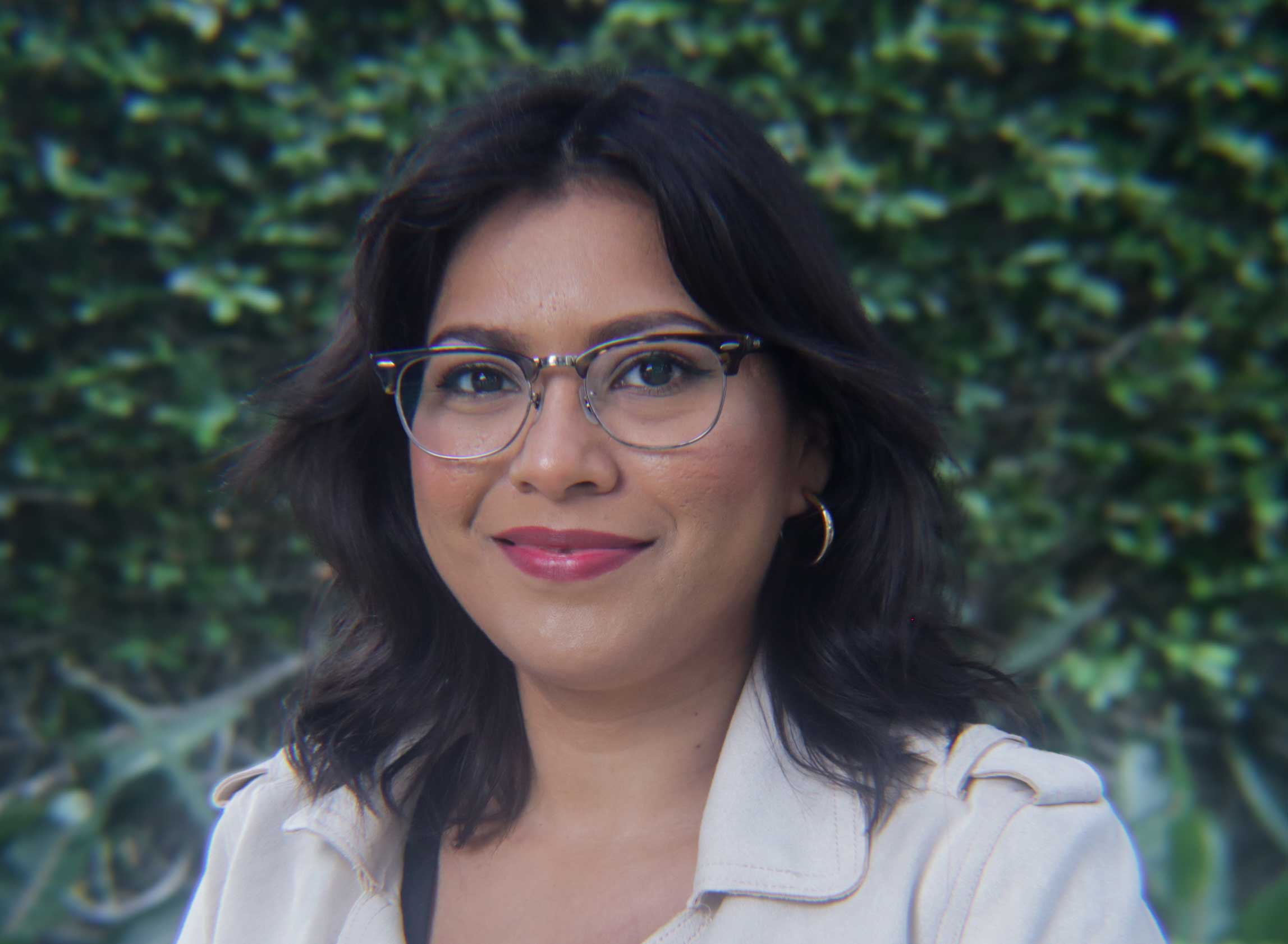 Hispanic woman with glasses smiling at camera